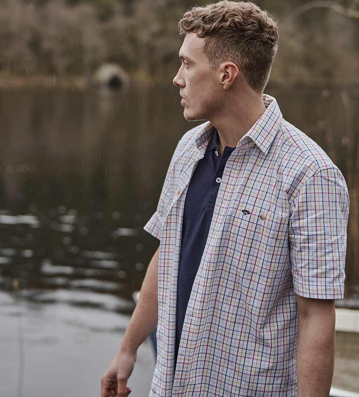 Men's Short Sleeve shirts country style. Man wears unbuttoned shirt with lake in background.