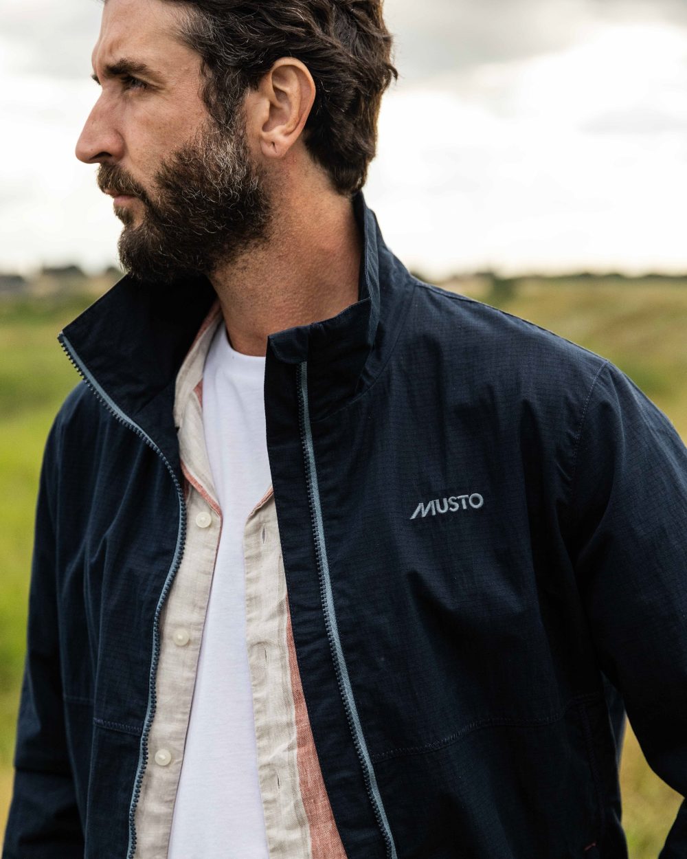 Navy Coloured Musto Mens Coastal Waterproof Jacket On A Coastal Background