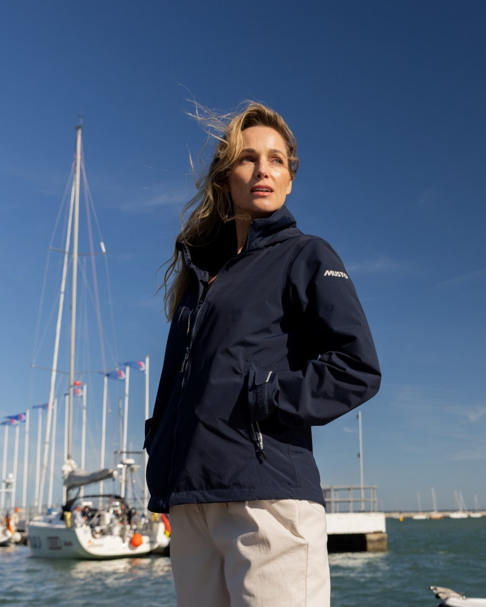 True Navy Coloured Musto Womens Corsica Jacket on Beach Background