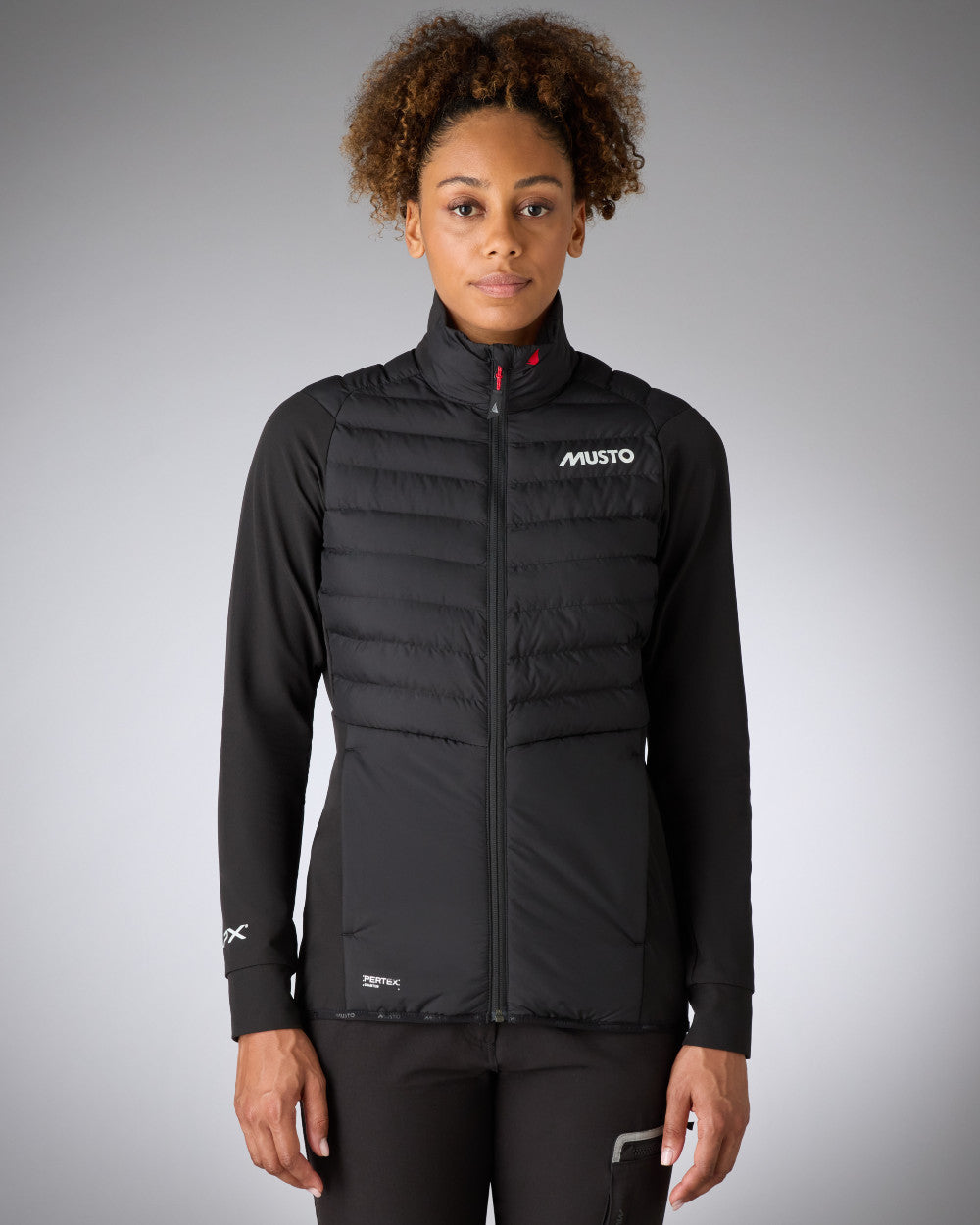 Black Coloured Musto Womens LPX Hybrid Jacket On A Grey Background