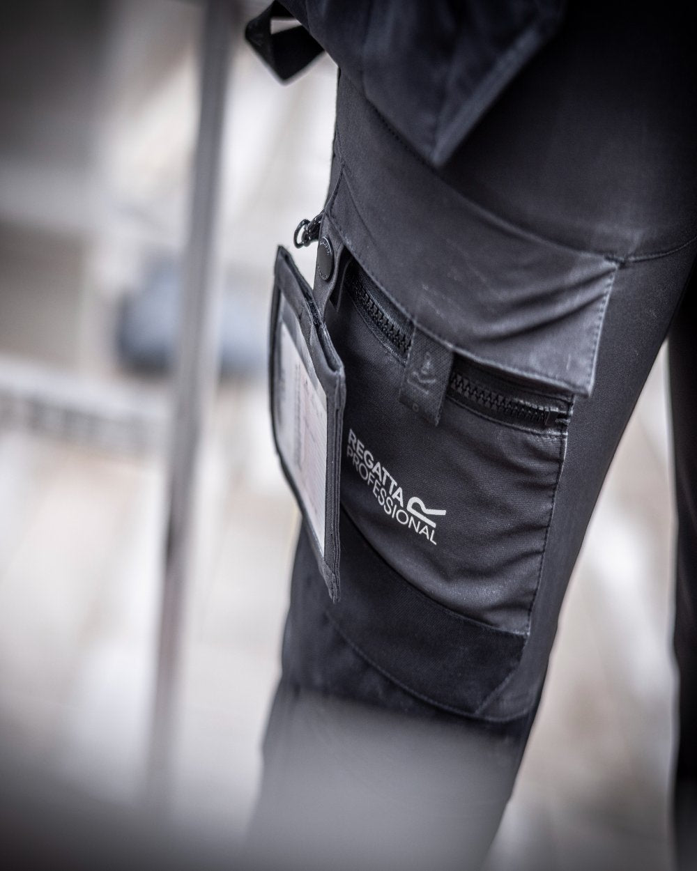 Black Orange Coloured Regatta Mens Hi-Vis X-Pro Stretch Holster Trousers Class 1 on Construction Site Background