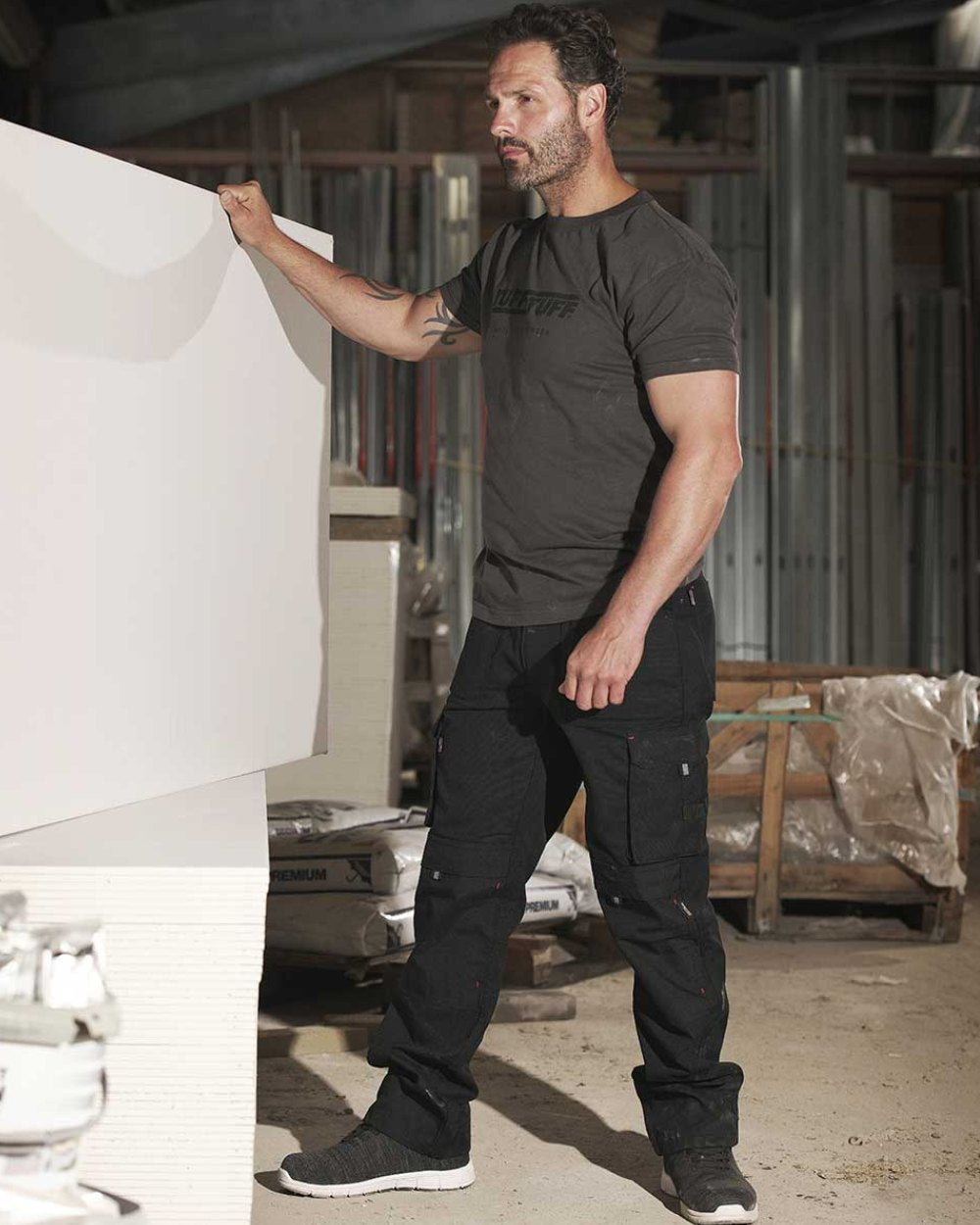 Black Coloured TuffStuff Extreme Work Trousers On A Warehouse Background