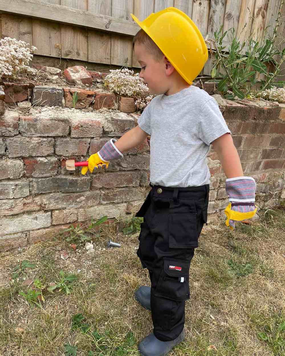 Black Coloured TuffStuff Junior Pro Work Trousers On A Backyard Background