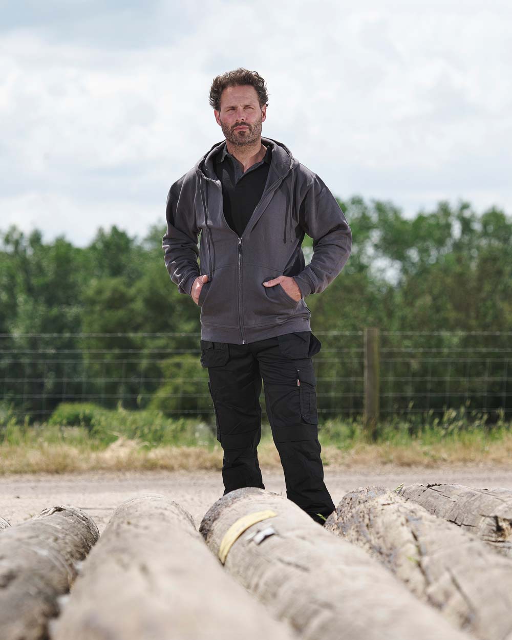 Grey coloured TuffStuff Pro Work Hoodie on Fence line background