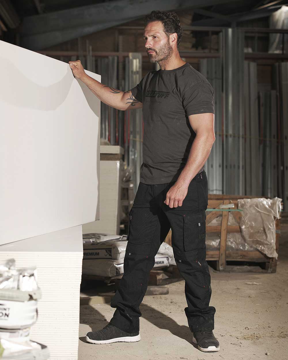 Man with plasterboard wearing TuffStuff Extreme Work Trousers in Black 