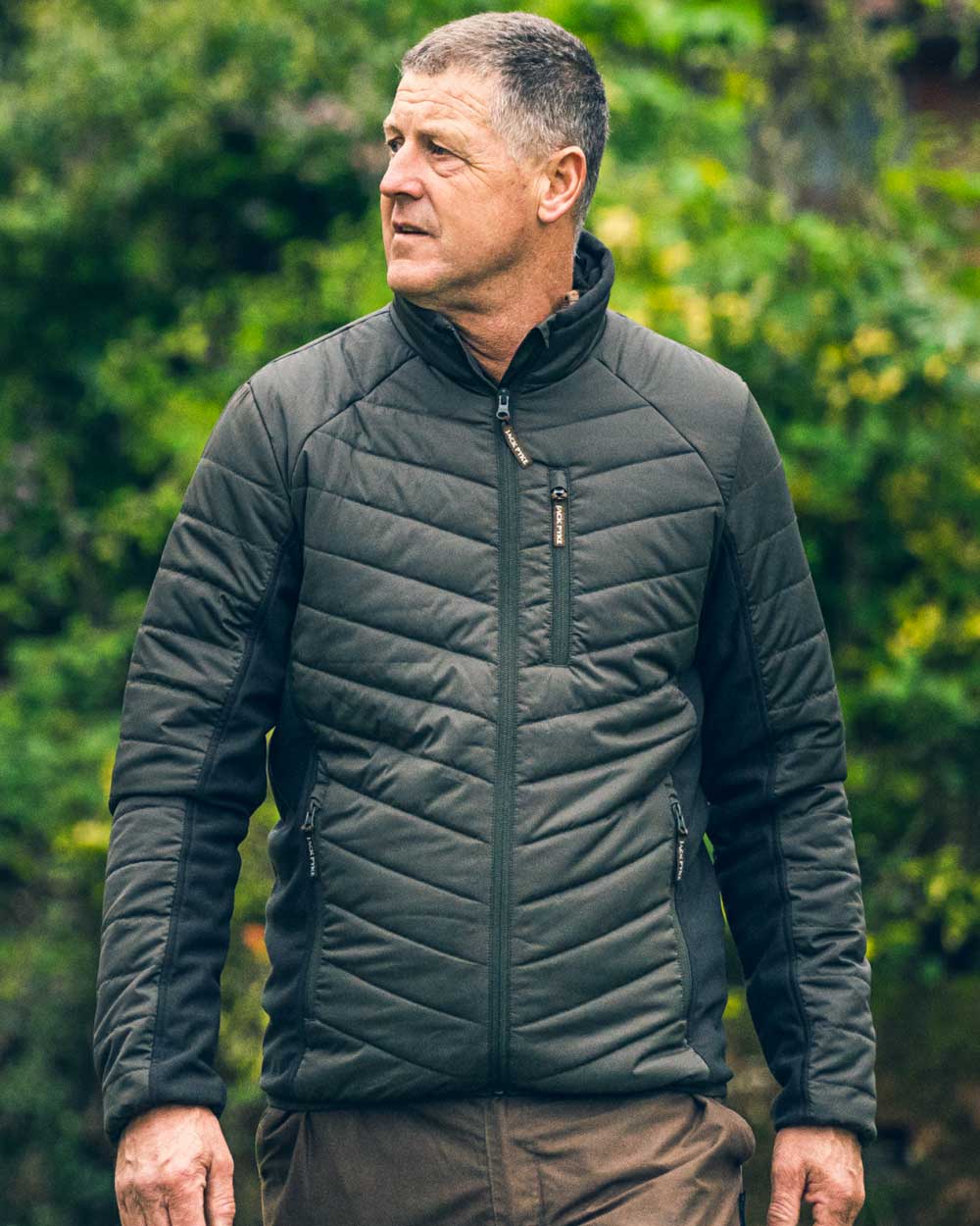 Green coloured Jack Pyke Hybrid Jacket on blurry background 