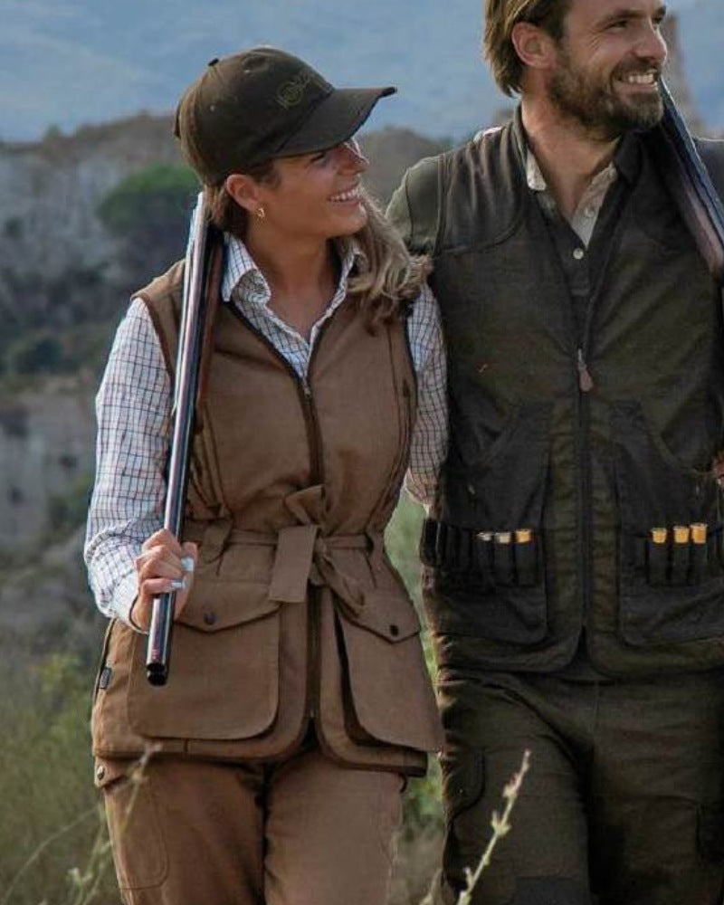 Woman wearing a Percussion women’s shooting gilet while carrying a shotgun outdoors in the countryside