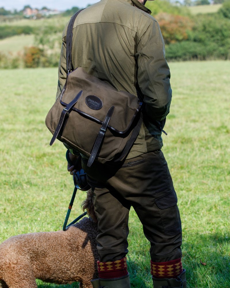 Person carrying a Jack Pyke field bag outdoors in a countryside setting