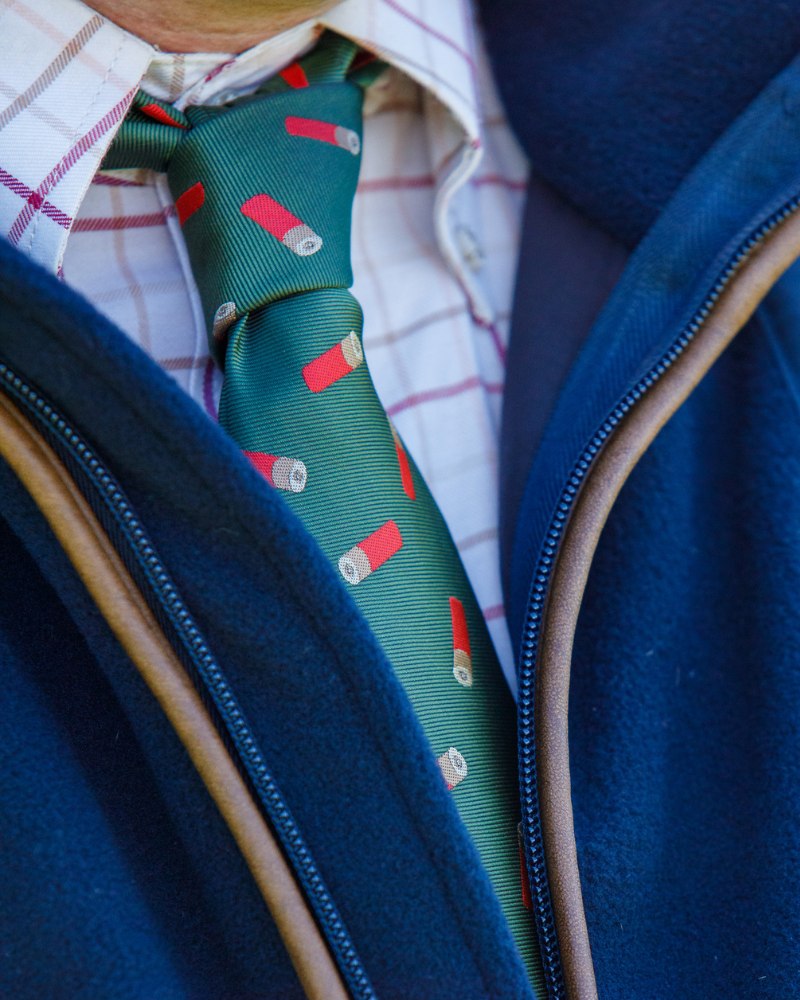 Close-up of a green Jack Pyke tie with shotgun cartridge pattern worn with country clothing