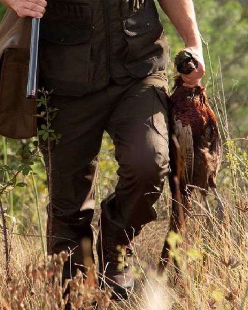 Person wearing Percussion hunting trousers while walking through tall grass during a countryside shoot