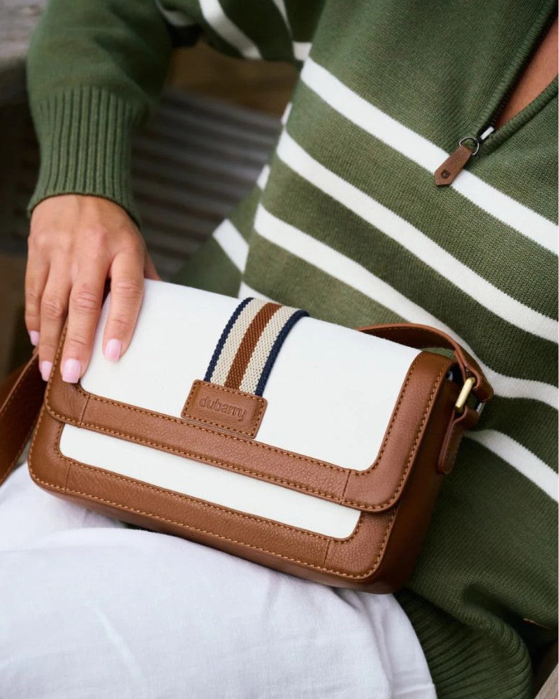 Person holding a Dubarry crossbody bag with tan leather trim and striped detail