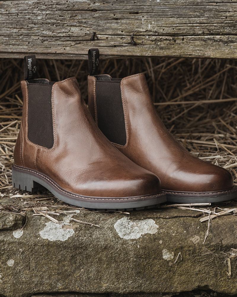 Pair of brown leather Hoggs of Fife dealer boots sat on a stone surface with a straw background. 