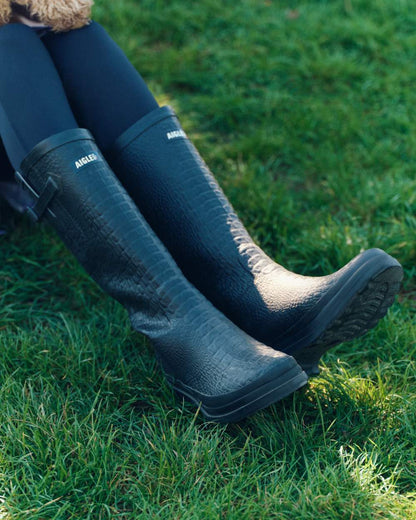 Noir coloured Aigle Womens Aiglentine 2 Crocodile Style Boots on grassy background 