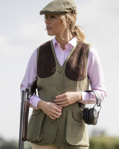 Juniper coloured Alan Paine Combrook Ladies Tweed Shooting Waistcoat on blurry background 