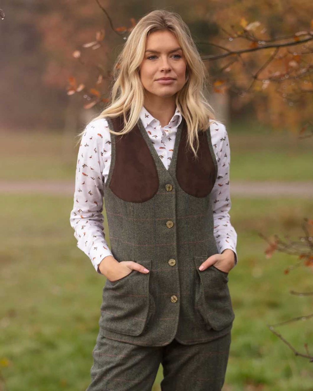 Spruce coloured Alan Paine Combrook Ladies Tweed Shooting Waistcoat on blurry background 