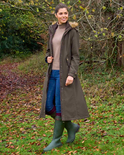 Olive coloured Alan Paine Ladies Dunswell Waterproof Long Coat on forest background 