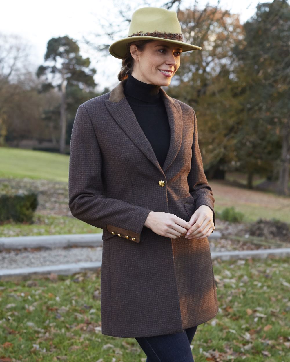 Bramble coloured Alan Paine Surrey Mid-Thigh Tweed Coat on blurry yard background 