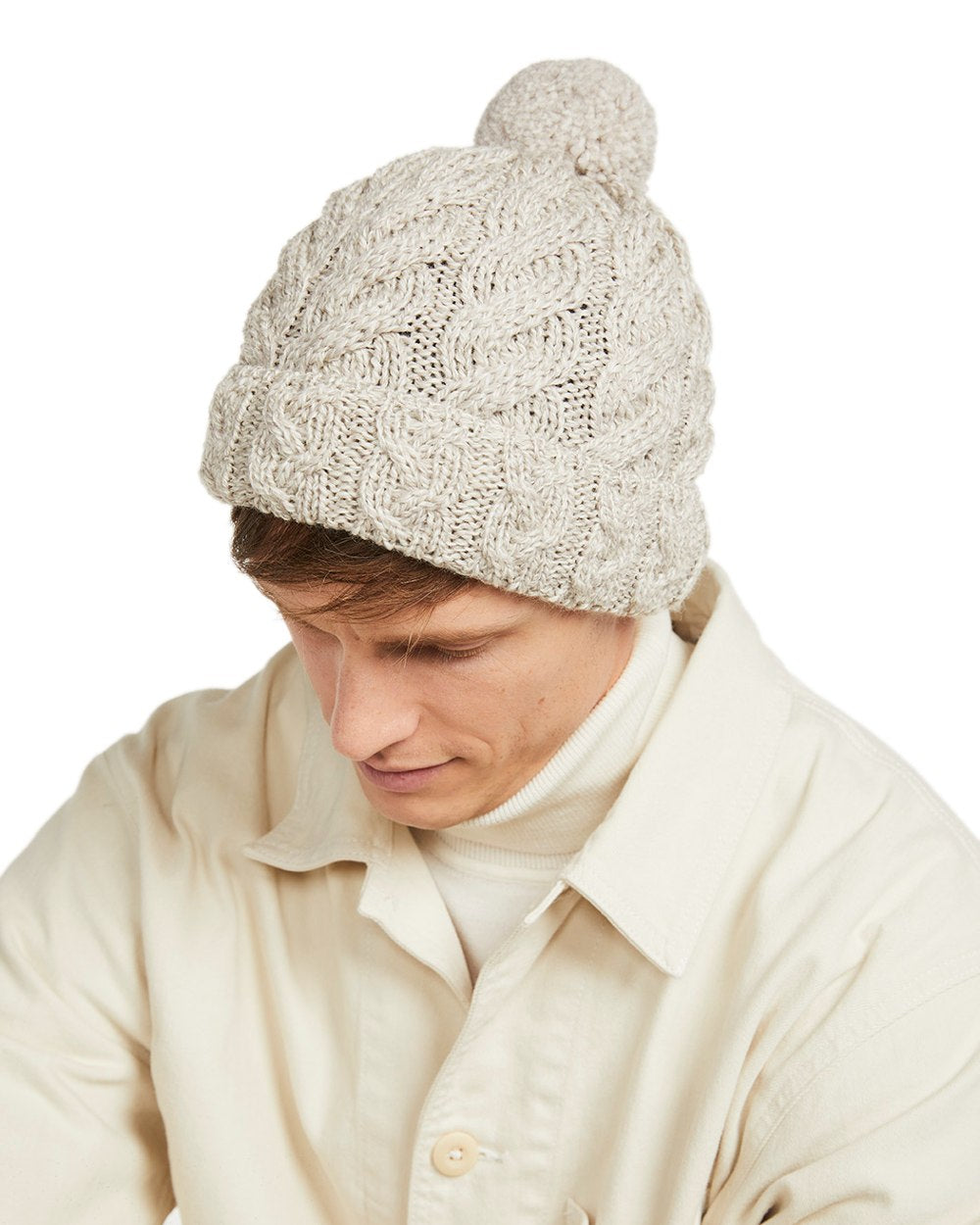 Beige Coloured Aran Chunky Knit Bobble Hat on white background 