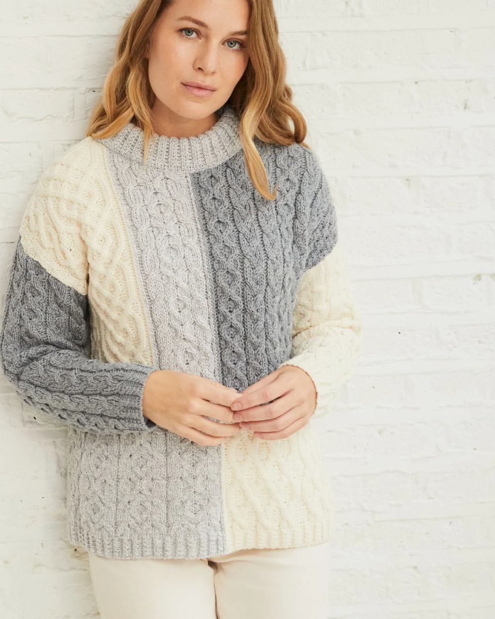 Dawn Coloured Aran Cobh Sweater on grey wall background 