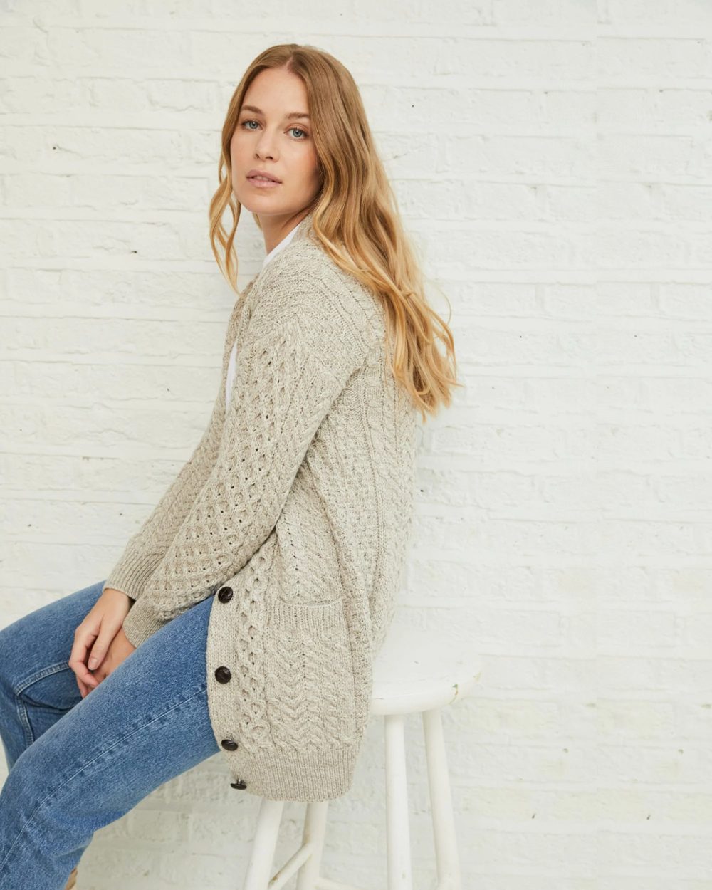 Oat Coloured Aran Delphi Boyfriend Cardigan on grey wall background 