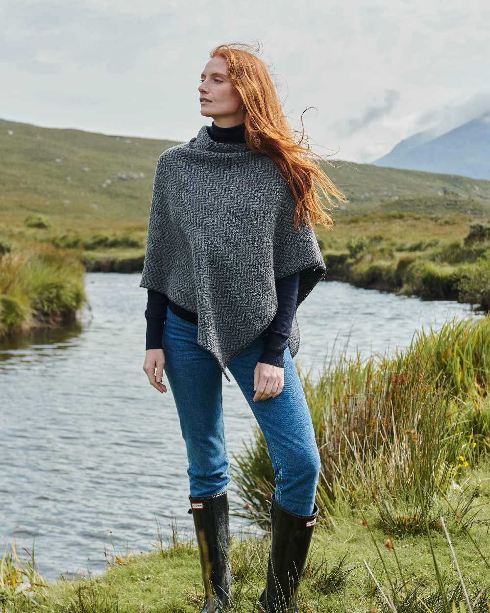 Charcoal Coloured Aran Herringbone Poncho with Buttons on pond background 