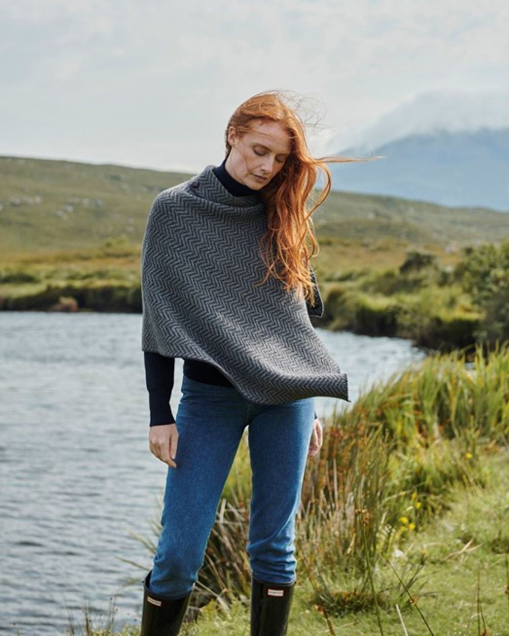 Charcoal Coloured Aran Herringbone Poncho with Buttons on pond background 