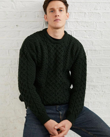 Forest Green Coloured Aran Inisheer Traditional Sweater on grey wall background 