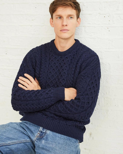 Navy Coloured Aran Inisheer Traditional Sweater on grey wall background 