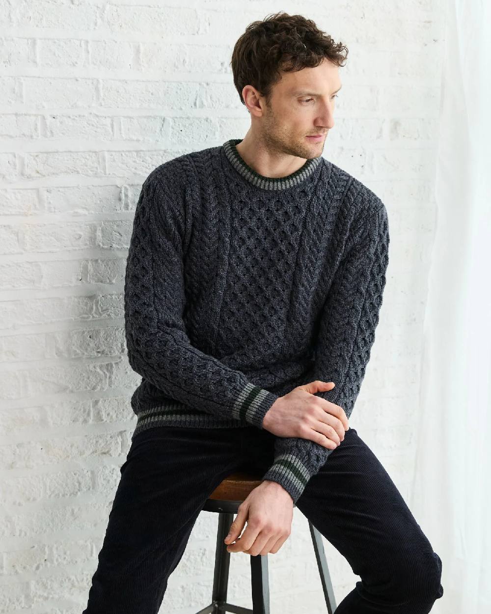 Dark Grey Coloured Aran Mens Inishbeg Stripe Crewneck Merino Sweater on indoor background 