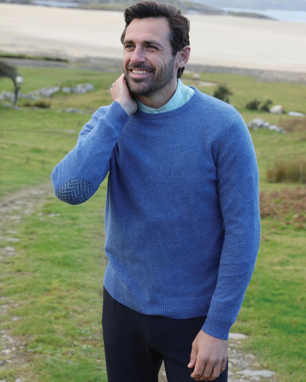 Blue Coloured Aran Merino Wool Crew Neck Sweater on land background 