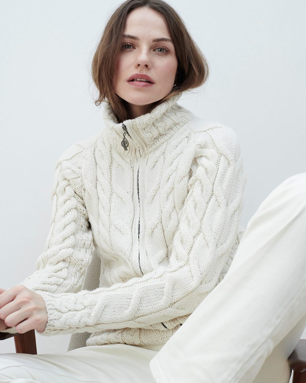 Cream Coloured Aran Merino Wool Full Zip Cardigan on grey wall background 