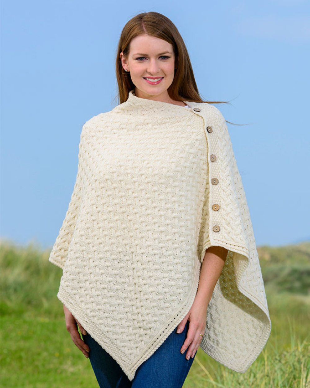 Cream Coloured Aran Merino Wool Knit Button Poncho on countryside background 