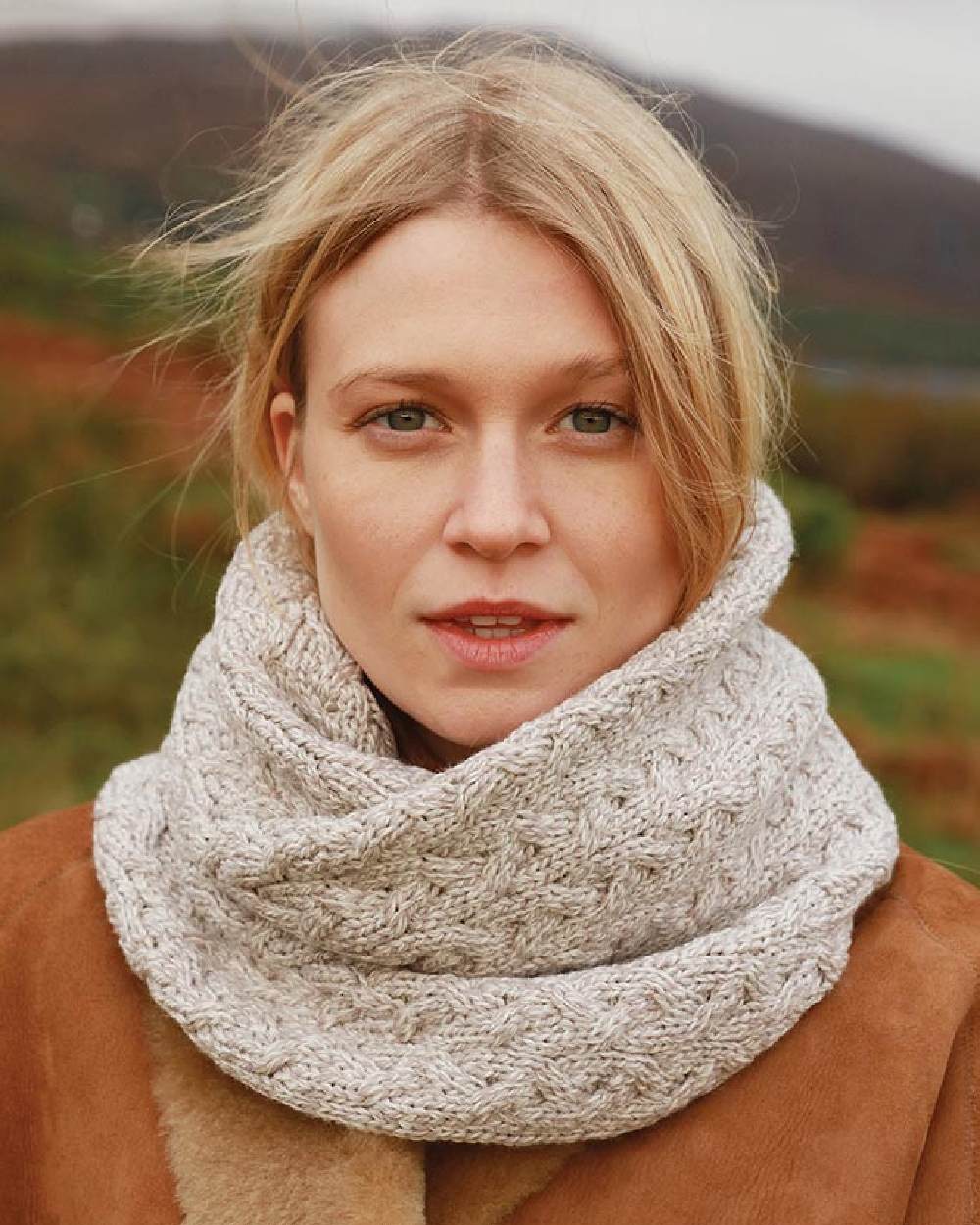 Oat coloured Aran Merino Wool Snood on blurry background 