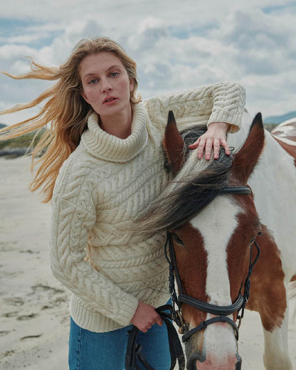 Cream Coloured Aran Womens Derreen Horizontal Cable Sweater on outdoor background 