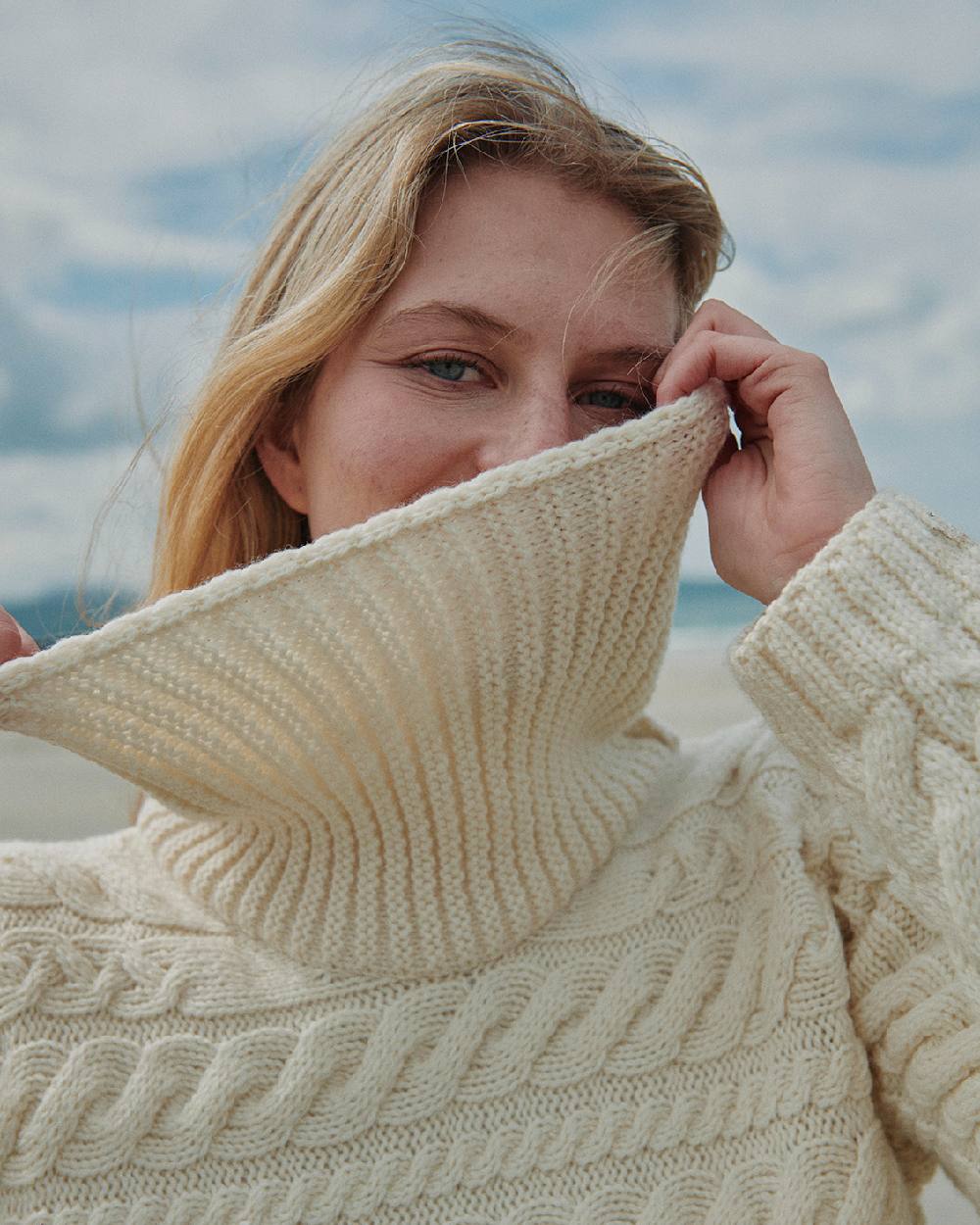 Cream Coloured Aran Womens Derreen Horizontal Cable Sweater on outdoor background 