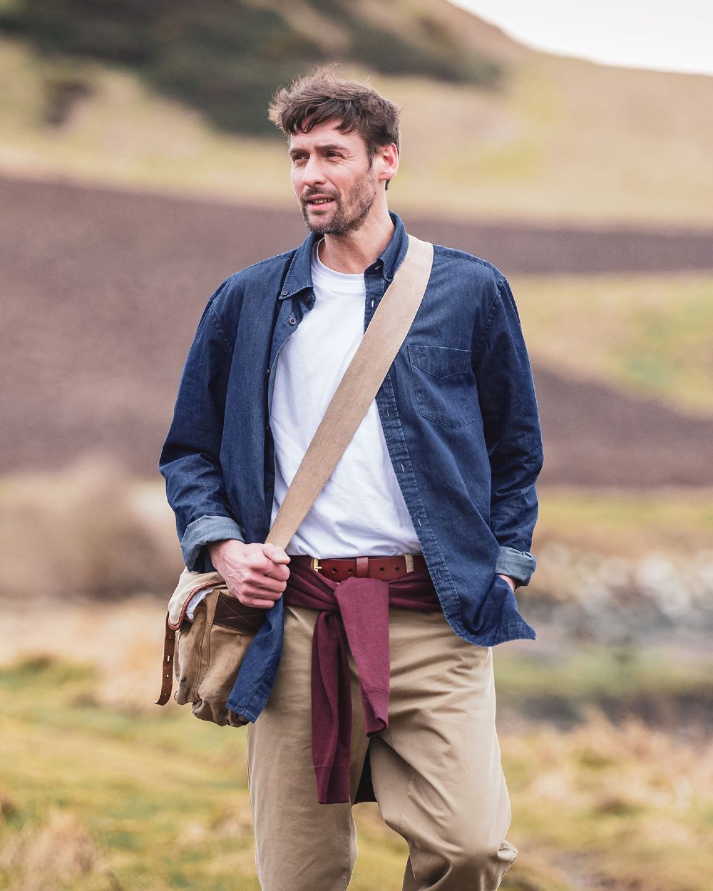 Dark wash coloured Hoggs of Fife Archerfield Denim Shirt on model with mountain background  