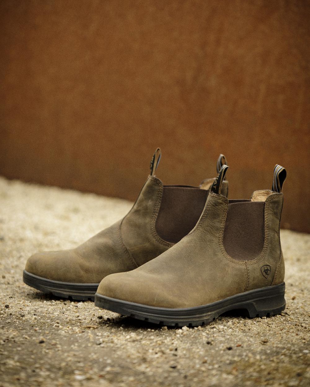 Distressed-Tan coloured Ariat Mens Cooper Chelsea Boots on wall background 