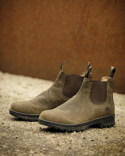 Distressed-Tan coloured Ariat Mens Cooper Chelsea Boots on wall background 