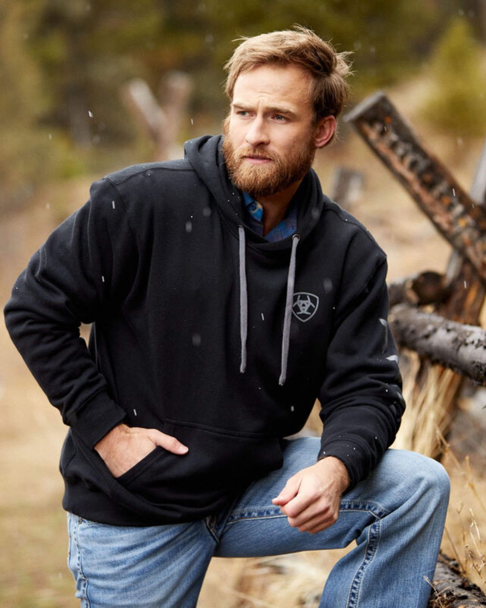 Black coloured Ariat Mens Logo Hoodie on a grass and tree background 