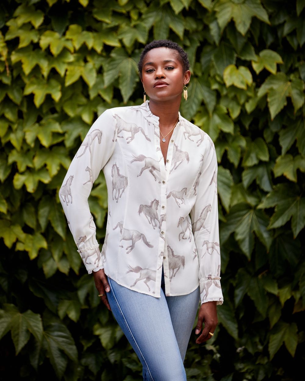 Sepia Horse Print Ariat Womens Clarion Blouse on blurry plant background 