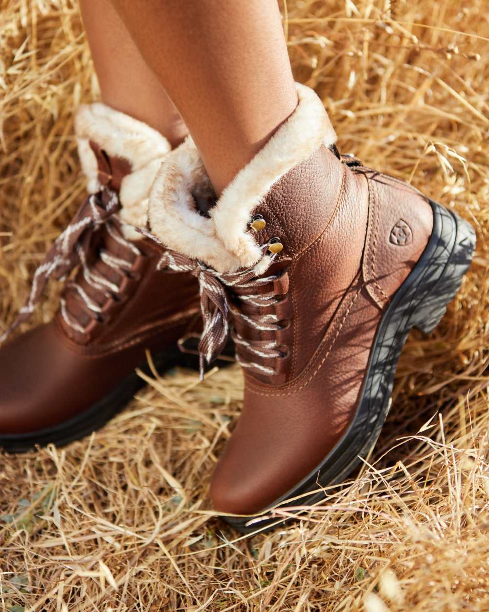 Dark Brown coloured Ariat Womens Harper Sherpa Waterproof Boots on hay background 