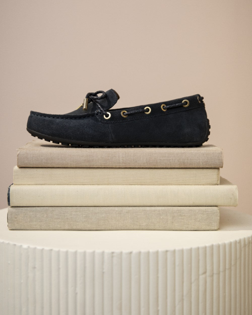 Navy Suede coloured Ariat Womens Margot Driving Moc on wall background 