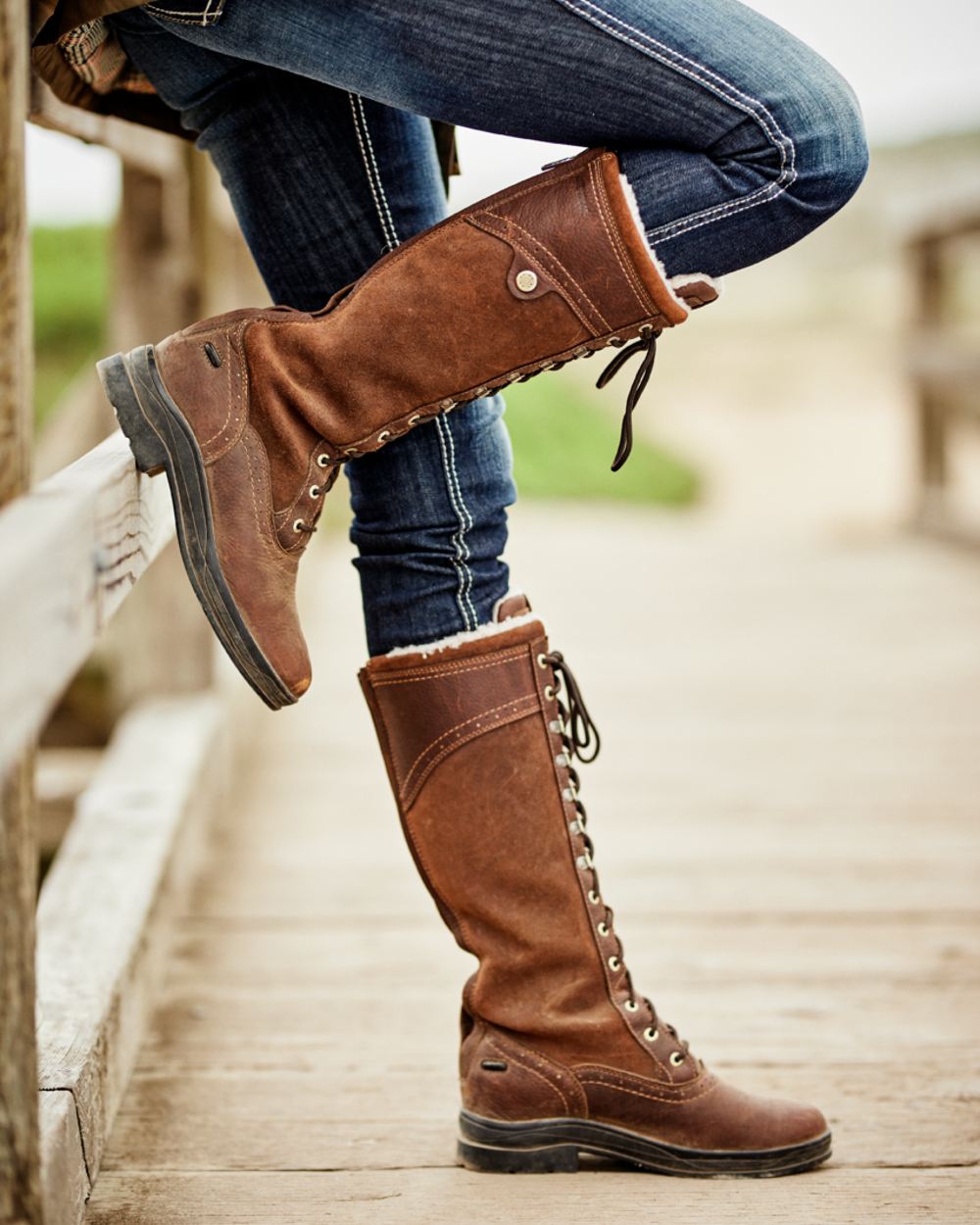 Dark Brown Coloured Ariat Wythburn Tall Waterproof Boots On A Countryside Background 