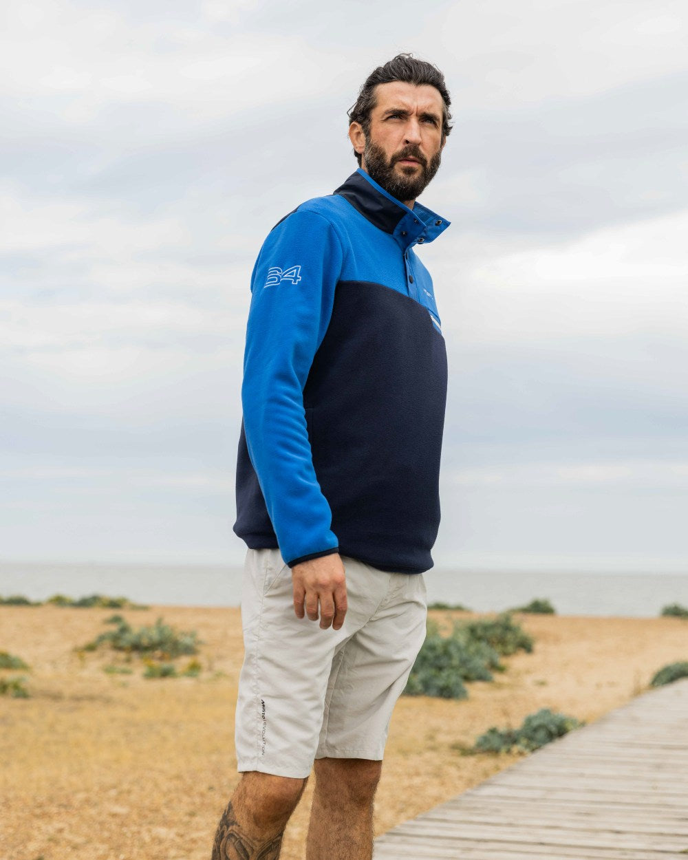 Aruba Blue/Navy Coloured Musto 64 Fleece Pullover On A Coastal Background 