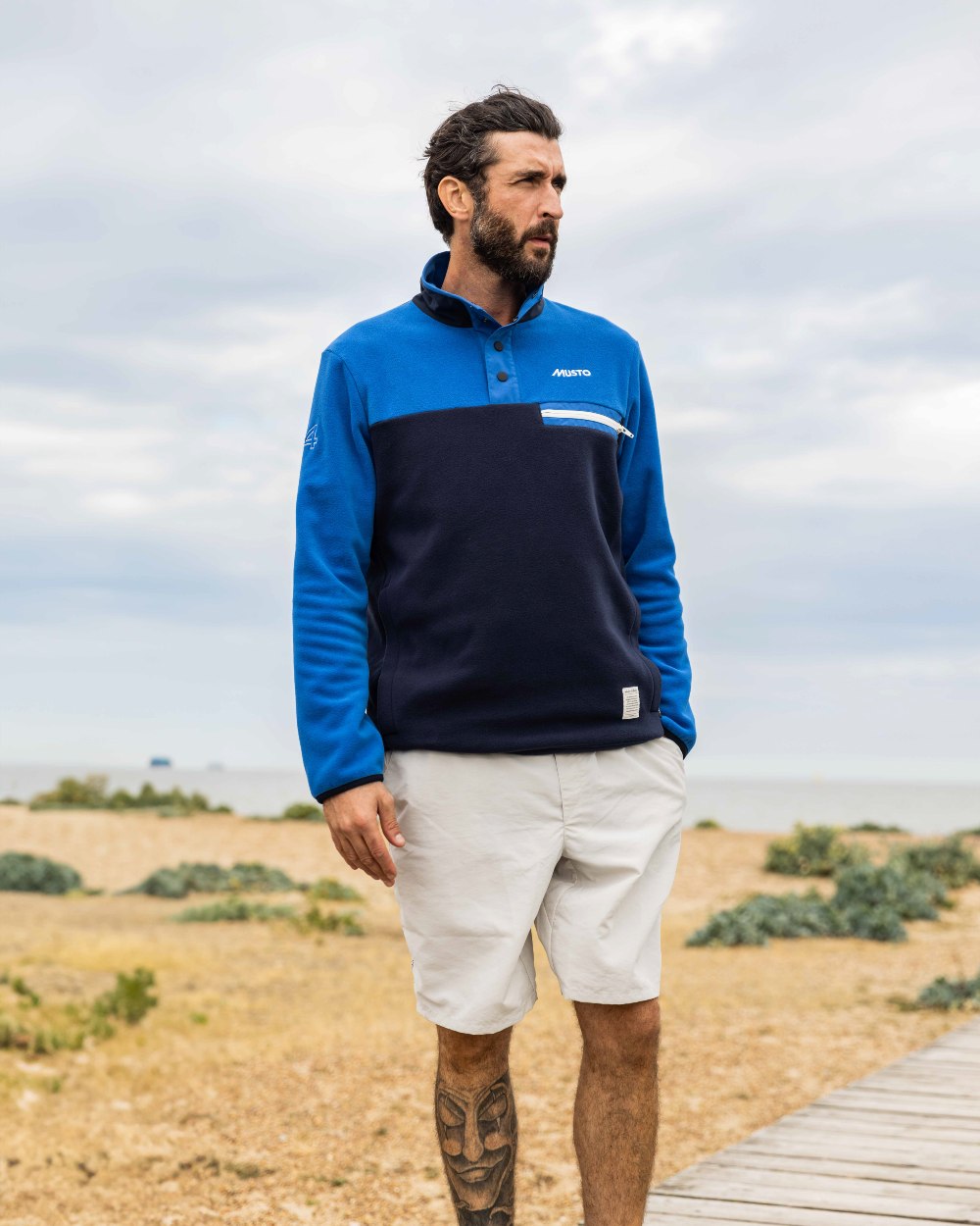 Aruba Blue/Navy Coloured Musto 64 Fleece Pullover On A Coastal Background 