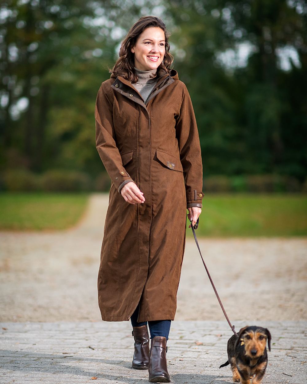 Earth Brown Coloured Baleno Kensington Long Waterproof Coat on blurry background 