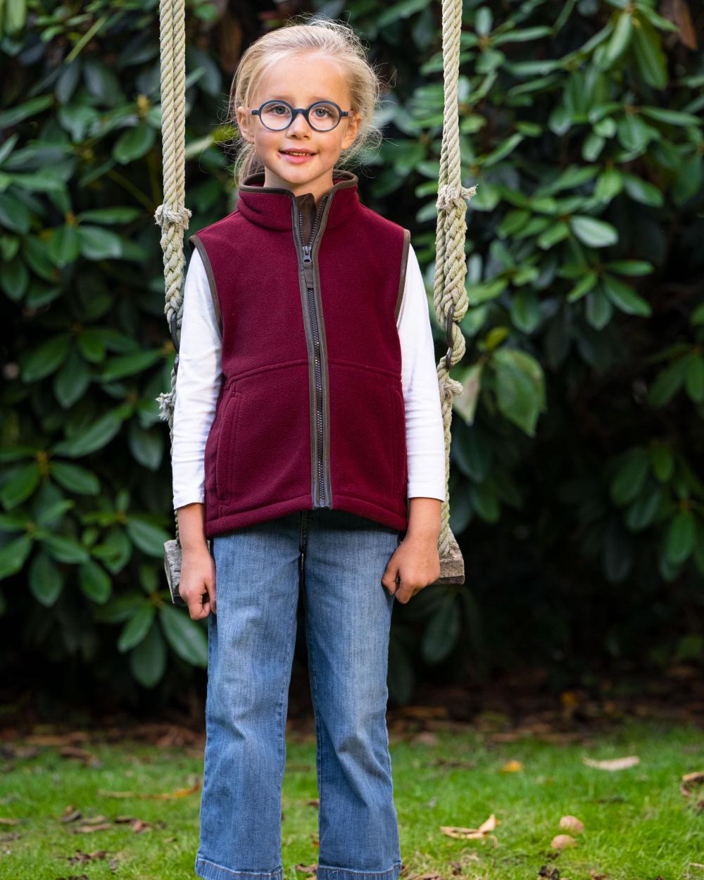 Burgundy Coloured  Baleno Wizz Kids Fleece Gilet on park background 