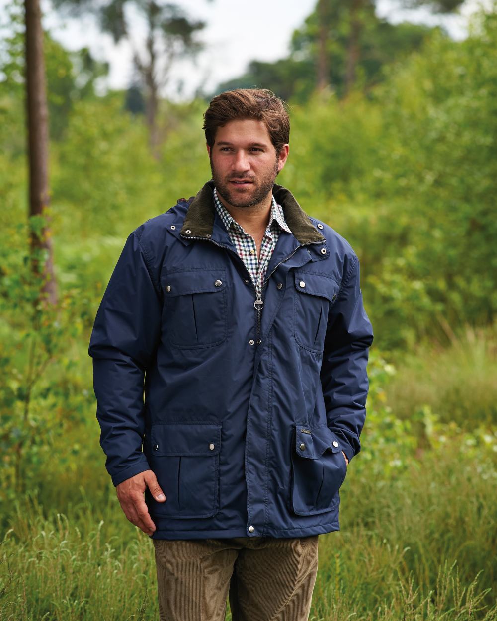 Navy coloured Champion Balmoral Waterproof Jacket on forest background 