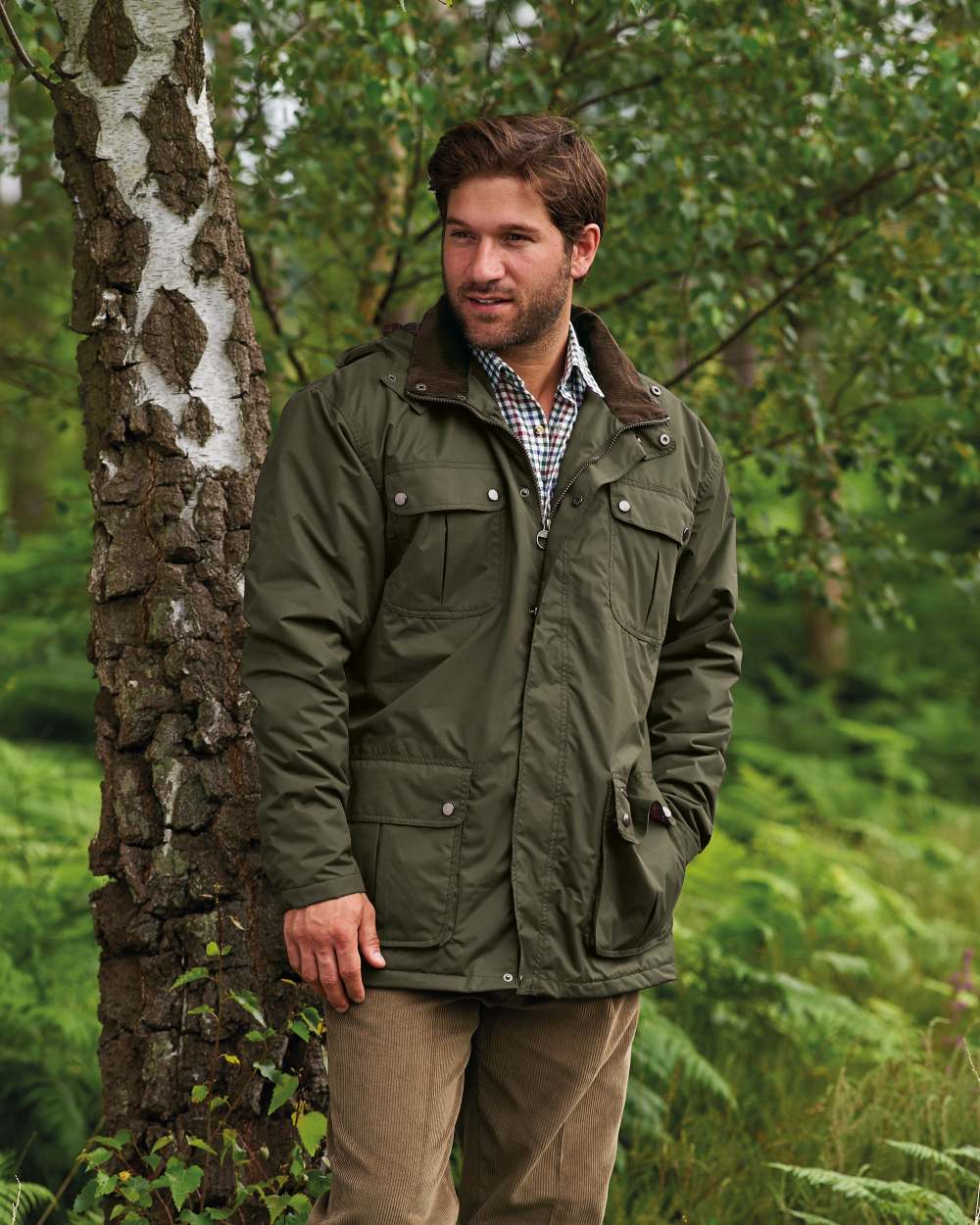 Olive coloured Champion Balmoral Waterproof Jacket on forest background 