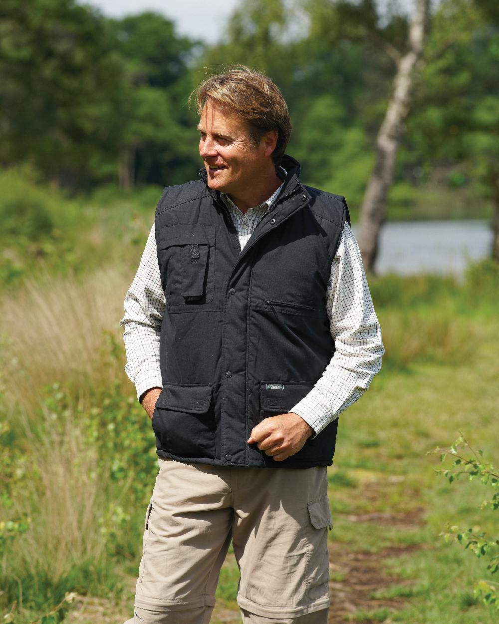 Black coloured Champion Peak Multi-Pocket Padded Bodywarmer on forest background 